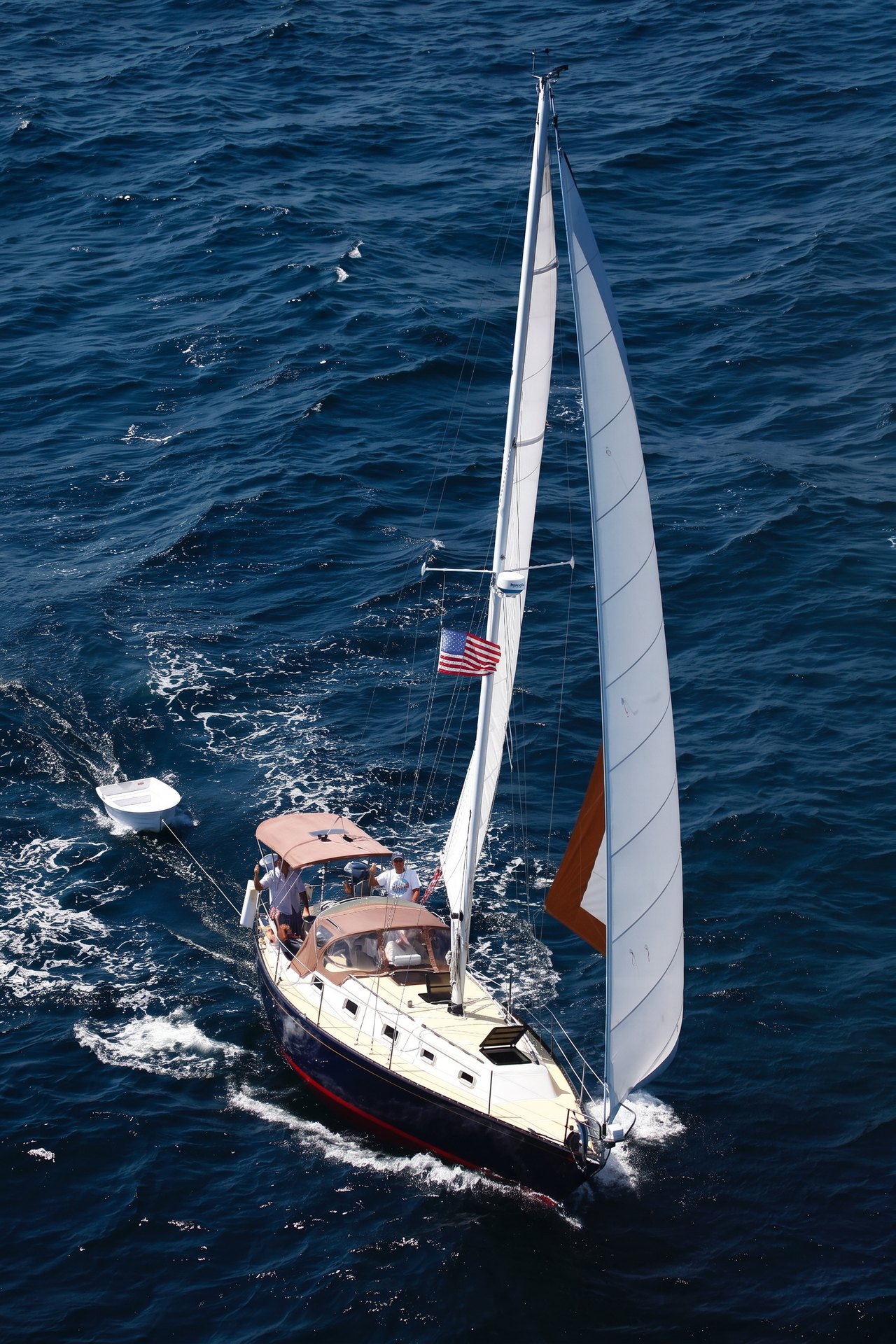 Second Wind classic yacht under sail, towing a dinghy